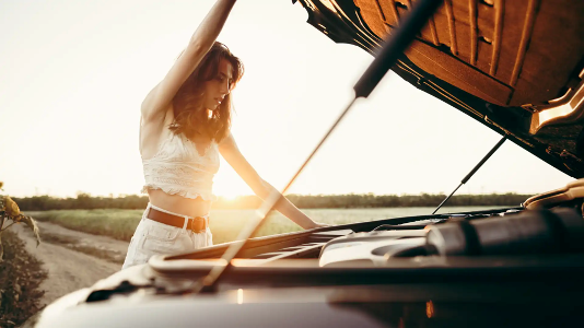 When does a car need a service – Woman looking at her car’s engine